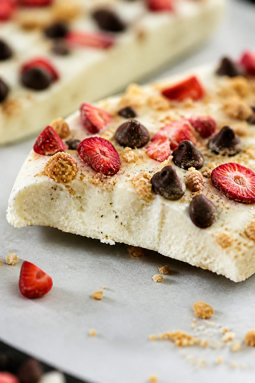Close-up detail: A shard of High Protein Cheesecake Protein Bark just out of the freezer, snapped ed