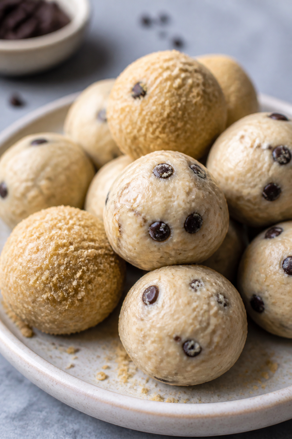Close-up detail: Freshly rolled cheesecake protein balls with mini dark chocolate chips folded in, a