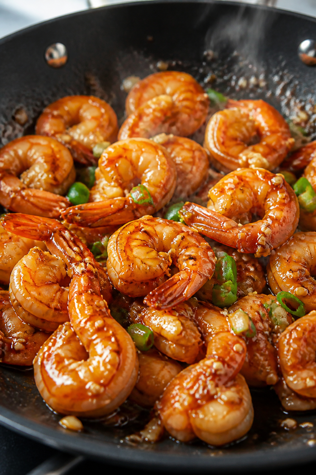 Close-up detail: Glossy honey-garlic shrimp just tossed back into the skillet, coated in a thick, ca