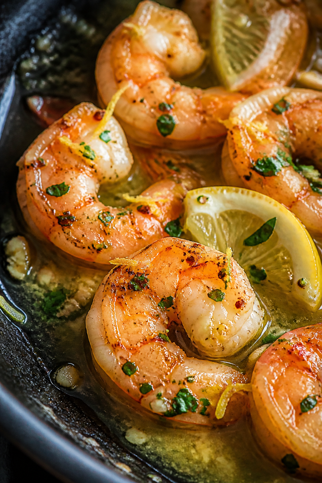 Close-up detail shot: Juicy, just-seared large shrimp in a skillet, coated in a glossy garlic-butter