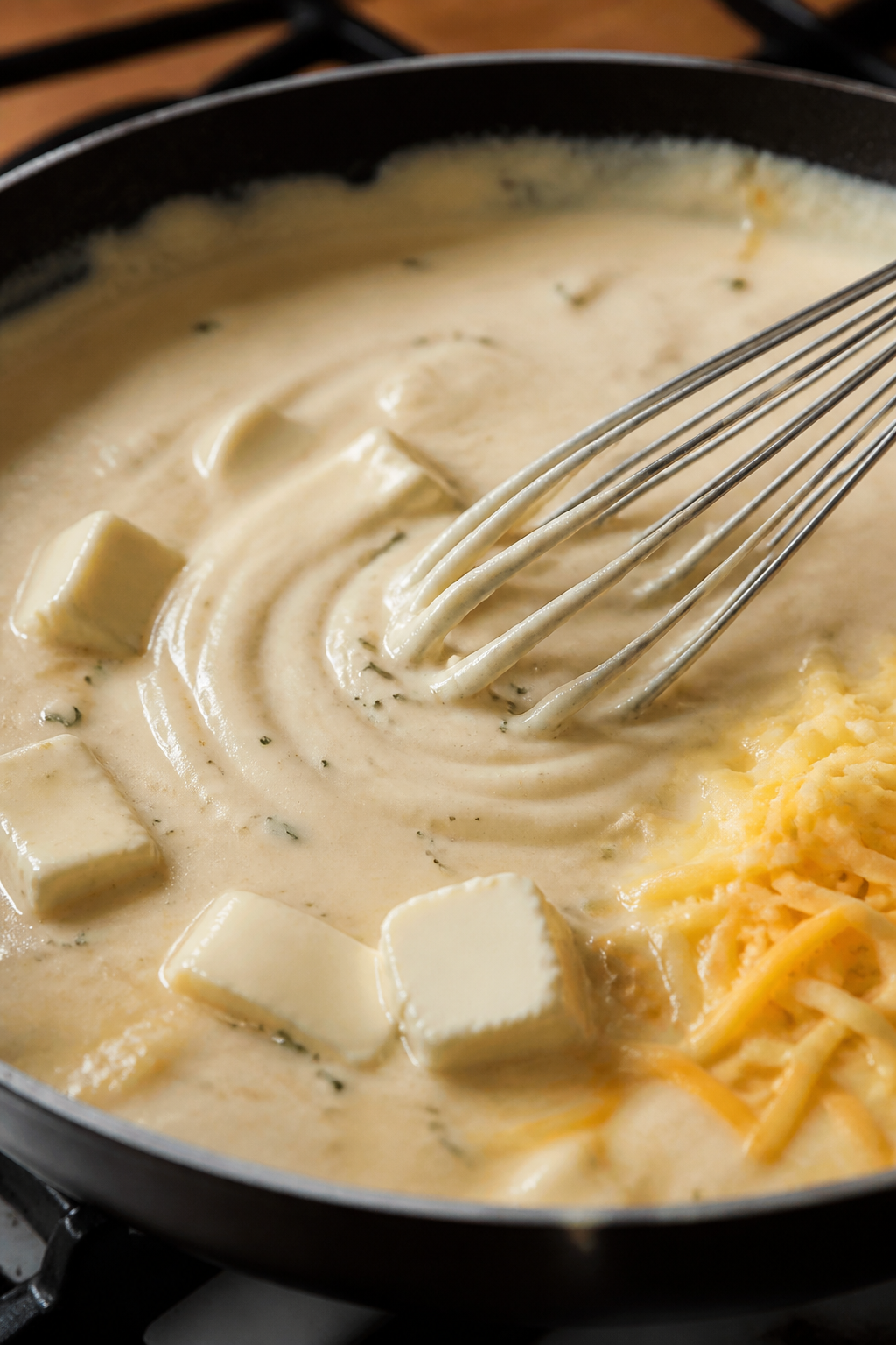 Cooking process: Creamy ranch cheese sauce being whisked smooth in a skillet—silky texture with ti