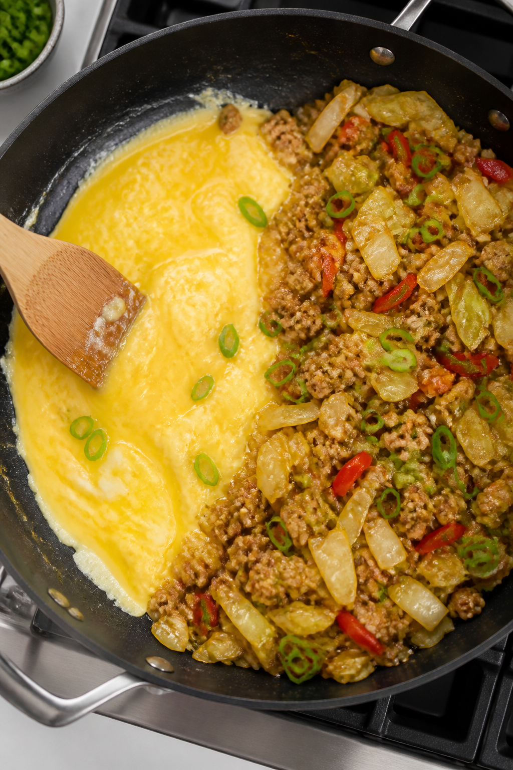 Cooking process: Egg roll in a bowl being prepared in one large skillet—mixture pushed to one side
