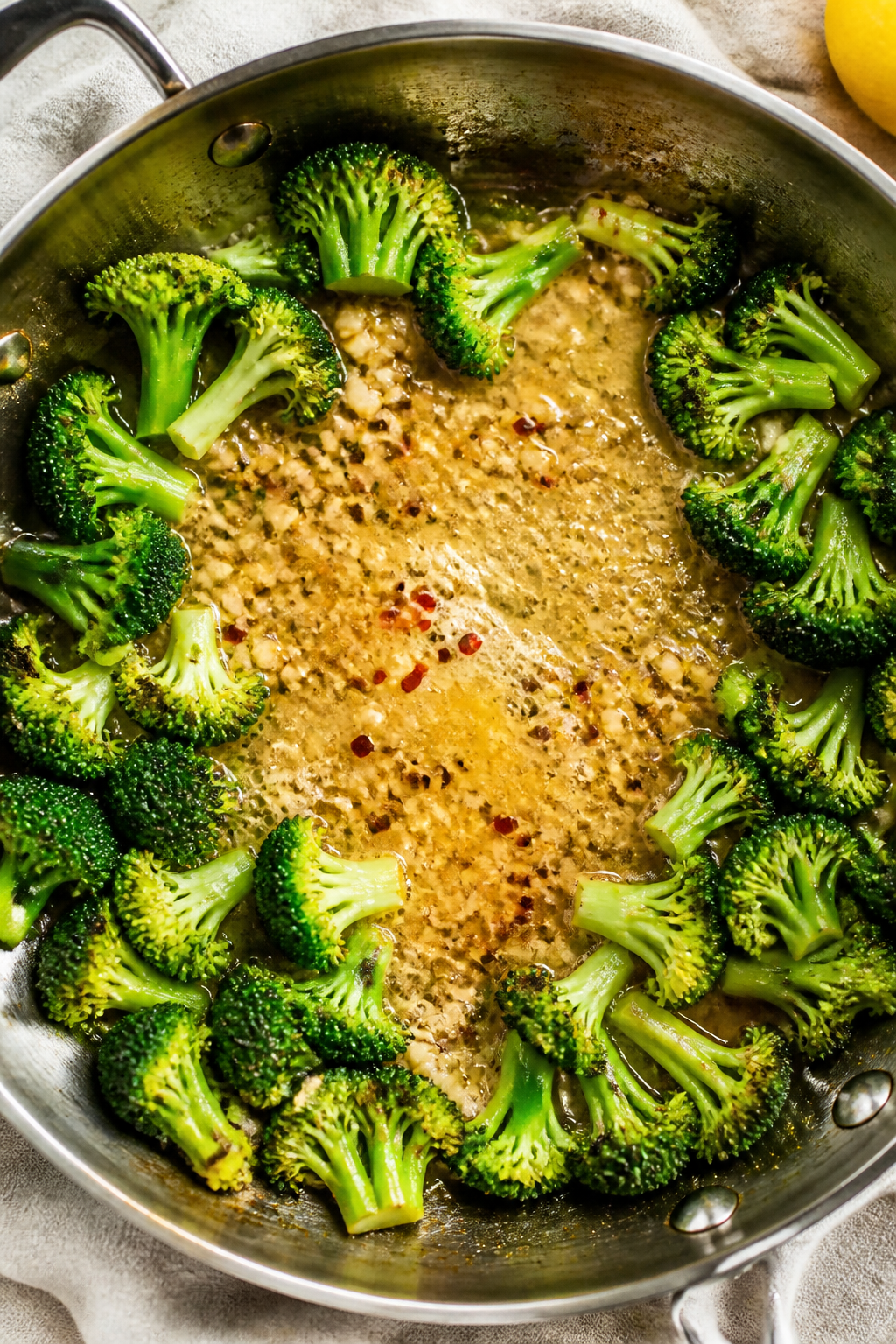 Cooking process: Overhead shot of the steam-sauté step—bright green broccoli pushed to the skille