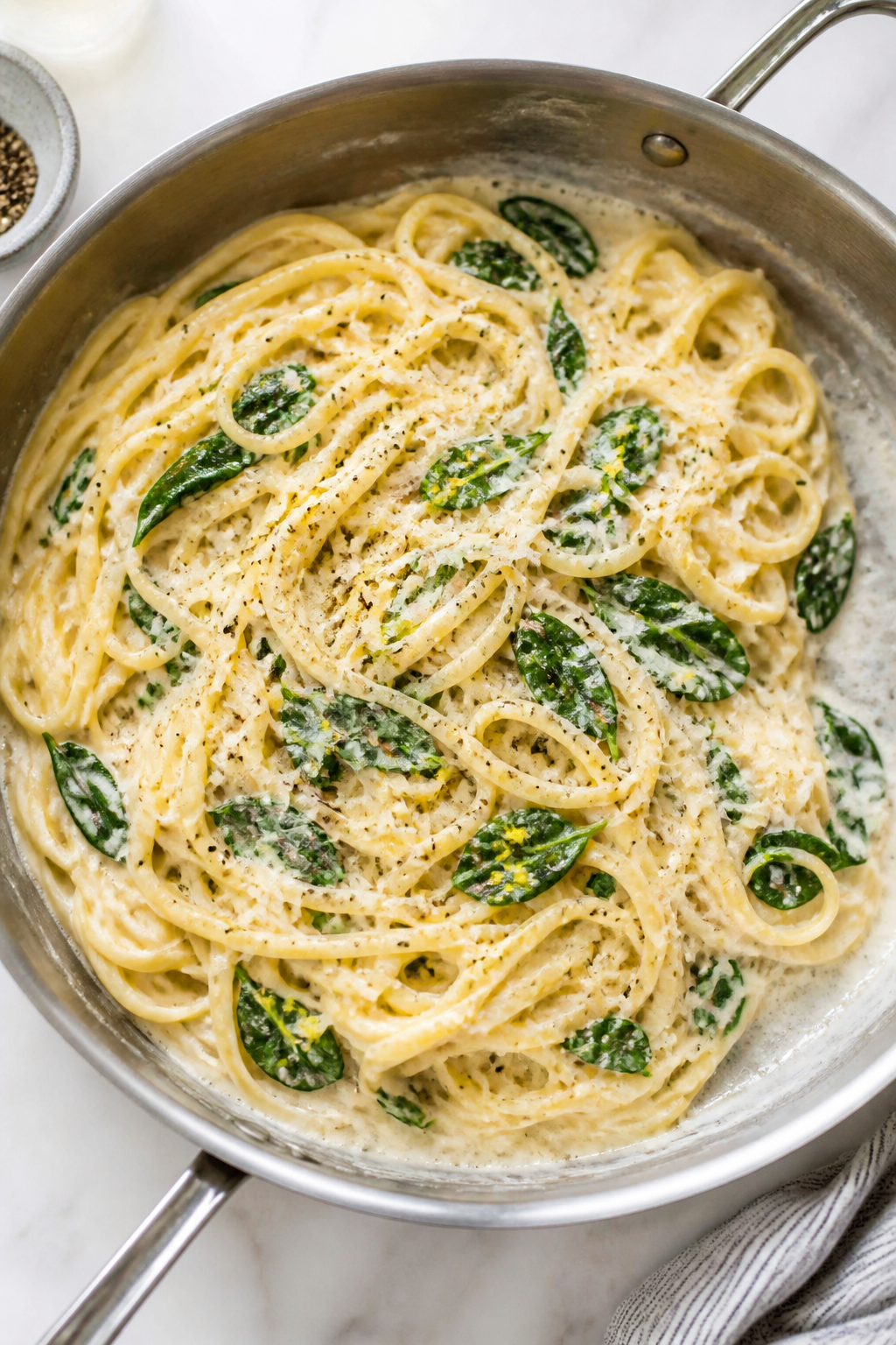 Tasty top view – Sauce toss with pasta: Overhead shot of linguine being tossed in a creamy, glossy