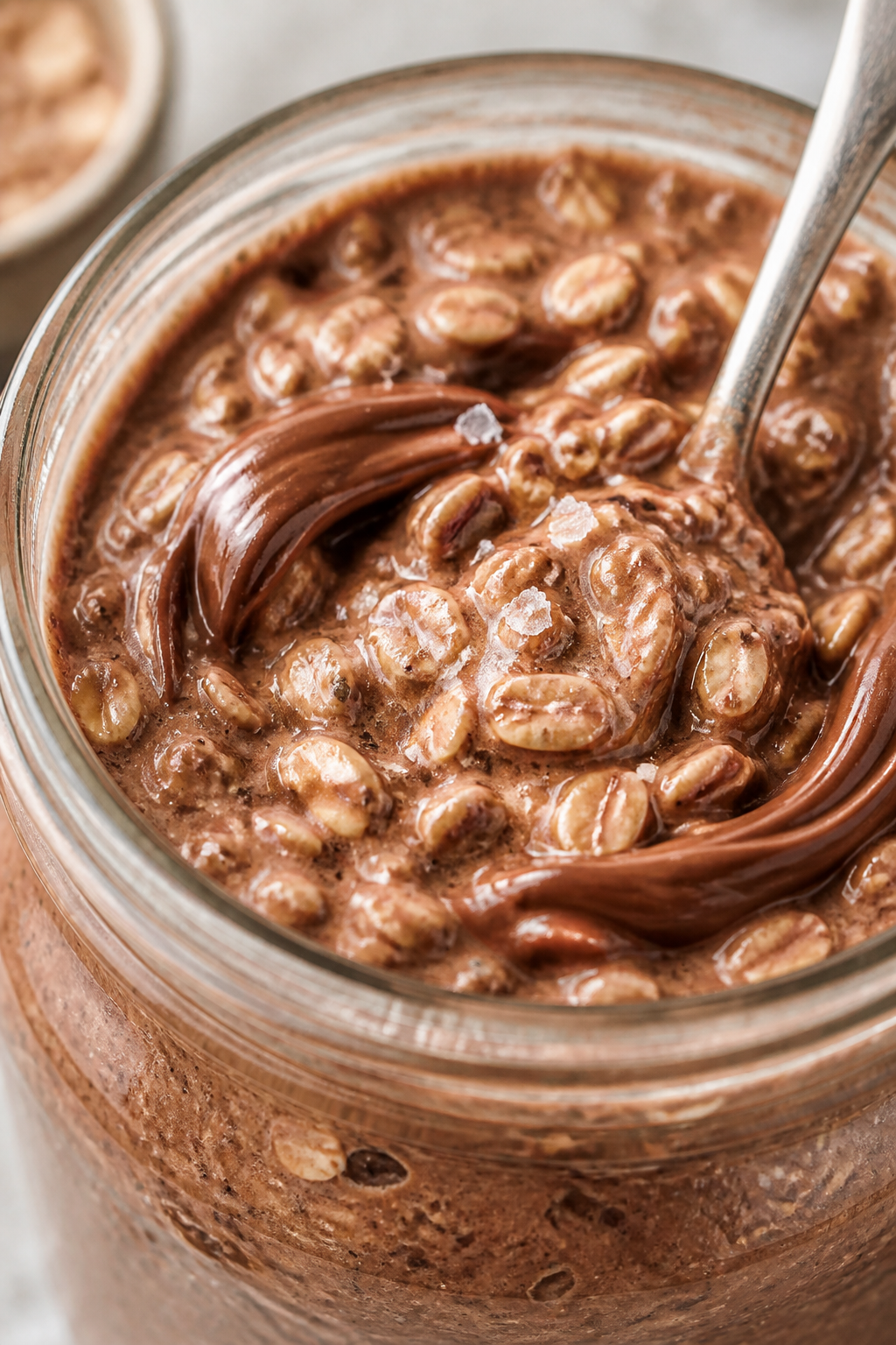 Close-up detail: A chilled jar of Chocolate Hazelnut Protein Overnight Oats just stirred after an ov