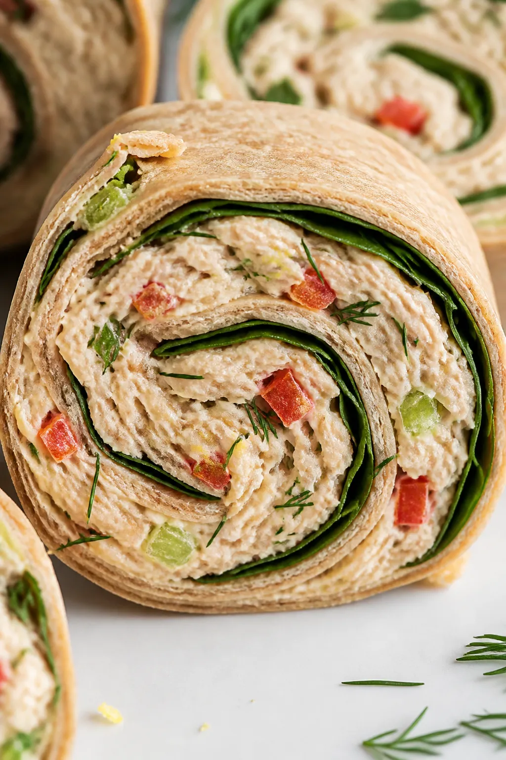 Close-up detail: A sliced tuna pinwheel showing tight, even spirals of whole-wheat tortilla wrapped