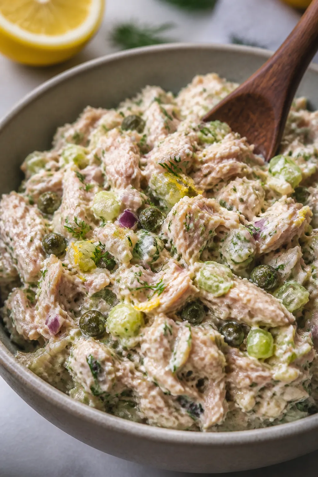 Close-up detail: Creamy tuna salad just mixed in a matte ceramic bowl, showcasing chunky flakes of t