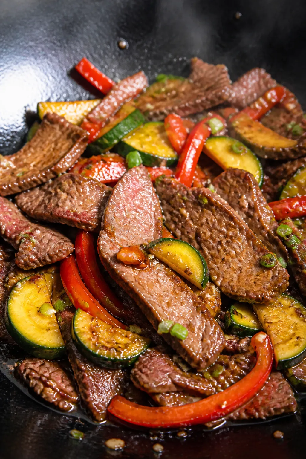 Close-up detail: Searing slices of beef in a wok, browned edges with slight pink centers glistening