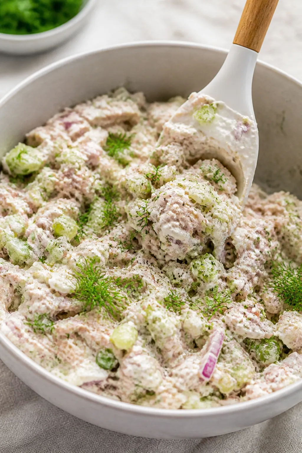 Close-up detail shot: A creamy bowl of prepared Cottage Cheese Tuna Salad being gently folded with a
