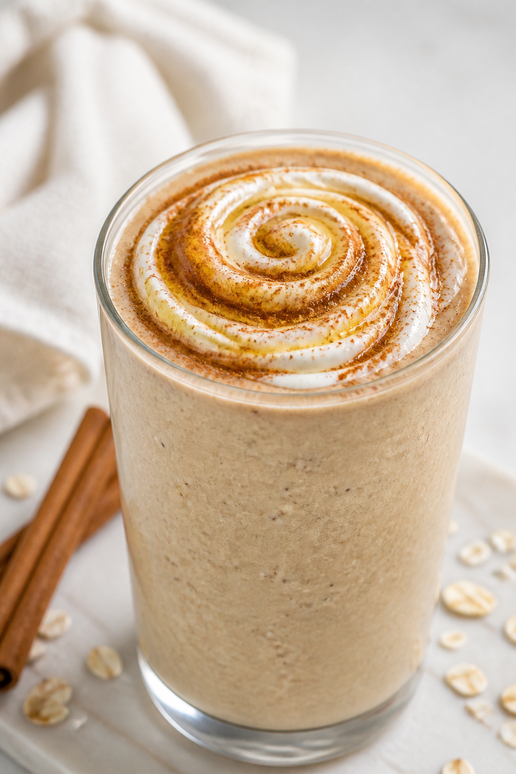 Close-up detail: Thick, creamy Cinnamon Roll Protein Smoothie just blended, poured into a clear chil