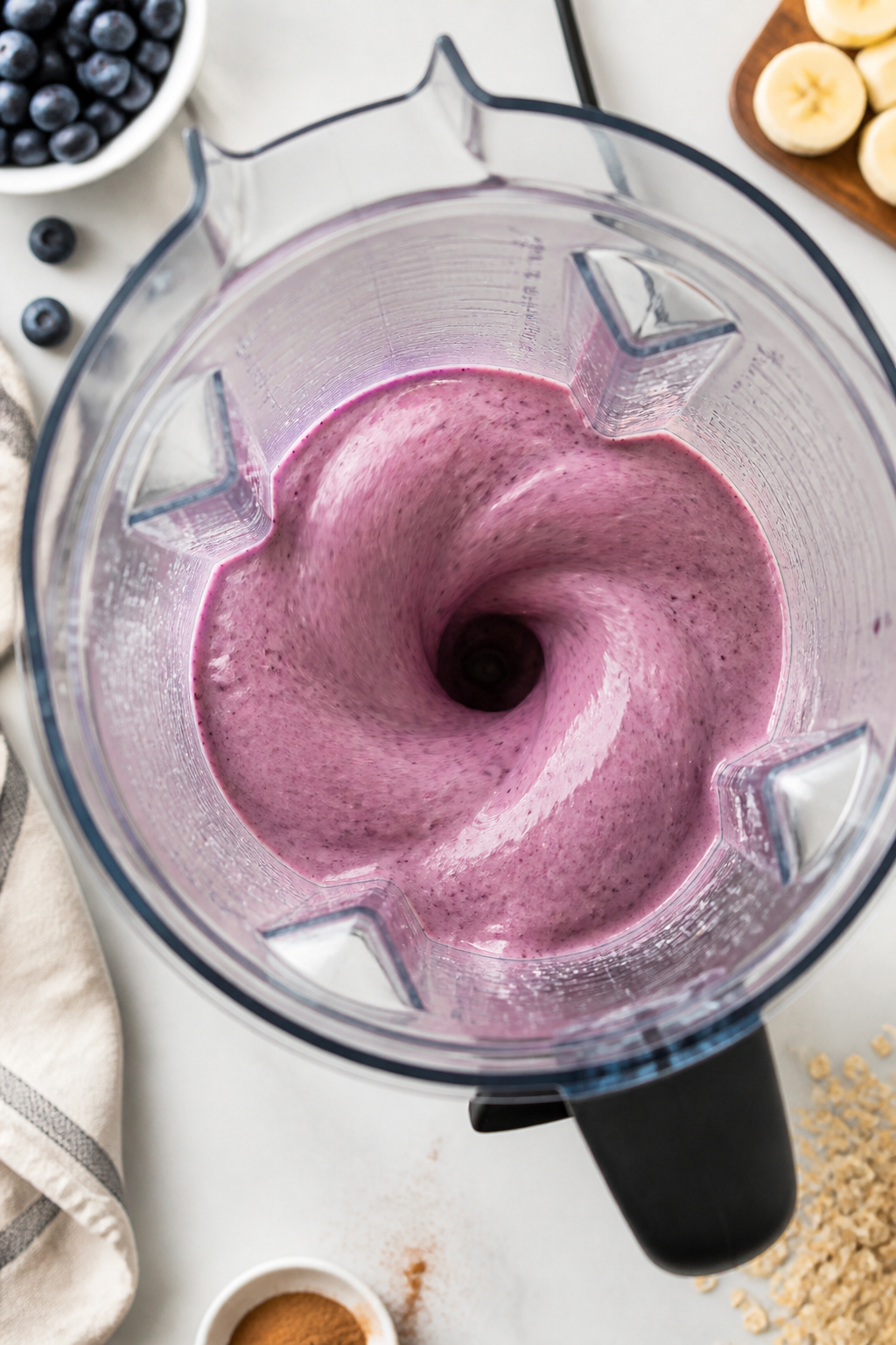 Cooking process: Overhead shot of the smoothie mid-blend in a high-speed blender, showing the layere