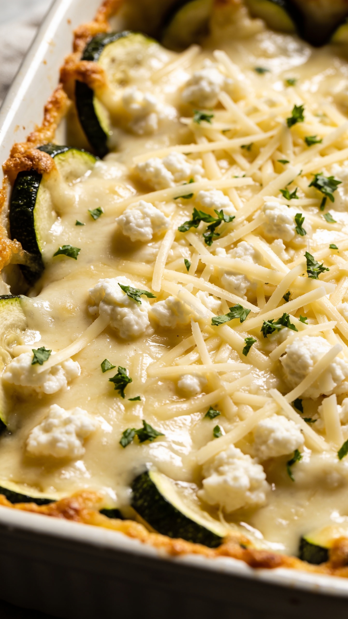 Close-up, top-down angle of the finished casserole with textures emphasized: glossy creamy sauce coating shredded mozzarella and cottage cheese, crispy golden edges around the zucchini, fresh herbs lightly sprinkled (optional parsley or oregano), dramatic shallow depth of field, bright natural light, 90–95% food fill, no utensils in view, premium plating aesthetic.